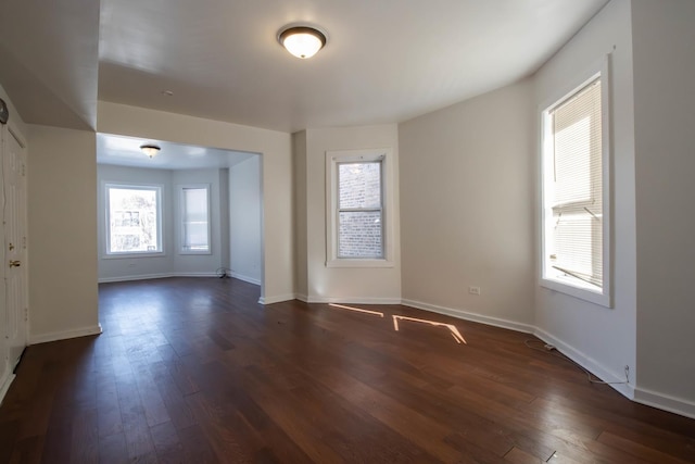 empty room featuring baseboards and dark wood-type flooring