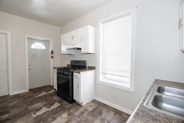 kitchen with under cabinet range hood, white cabinets, black gas range, and baseboards