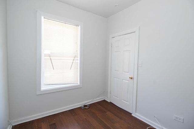 unfurnished room with dark wood finished floors and baseboards