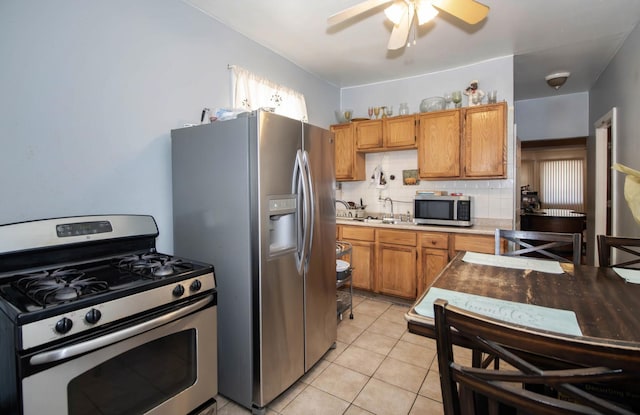 kitchen with light tile patterned floors, tasteful backsplash, ceiling fan, stainless steel appliances, and light countertops