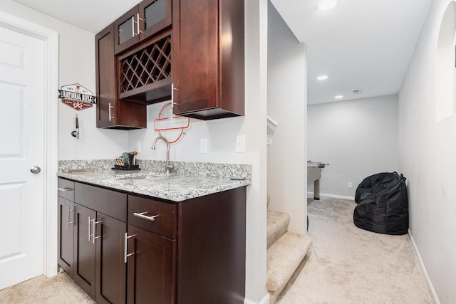 bar featuring light colored carpet, a sink, and baseboards