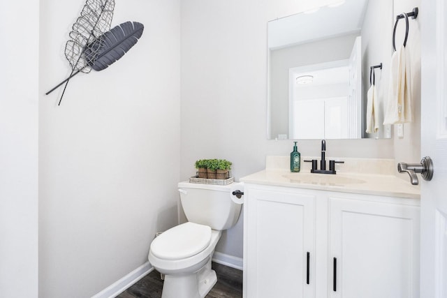 bathroom with wood finished floors, vanity, toilet, and baseboards