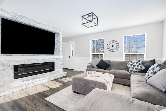 living room featuring dark wood-style floors, wainscoting, a fireplace, and a healthy amount of sunlight