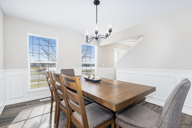 dining space featuring dark wood-style floors, visible vents, a notable chandelier, and wainscoting