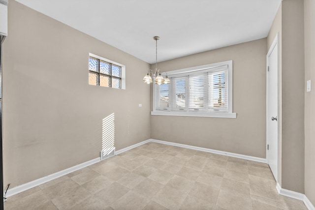 empty room with baseboards and a chandelier