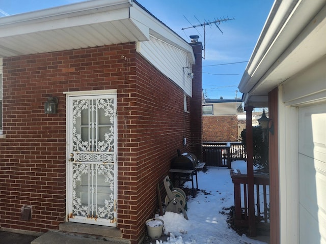 snow covered property featuring brick siding