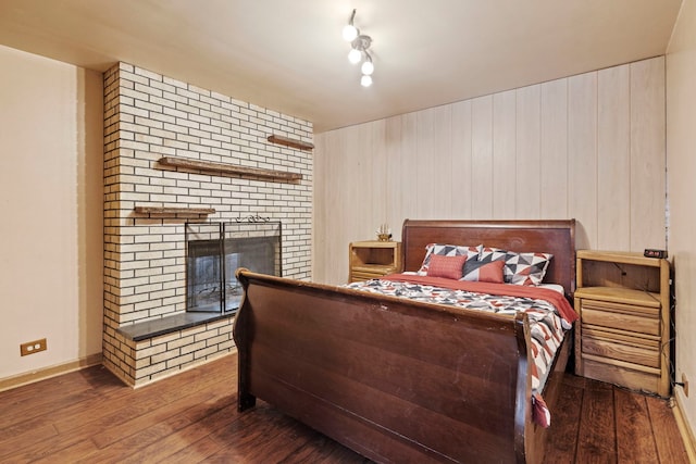 bedroom with dark wood finished floors, a fireplace, and baseboards