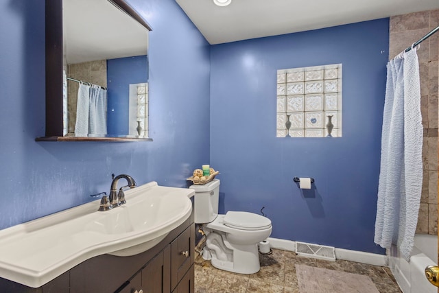 bathroom featuring toilet, vanity, visible vents, baseboards, and shower / tub combo with curtain