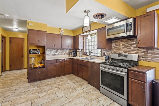 kitchen with stainless steel appliances, a sink, visible vents, dark brown cabinets, and tasteful backsplash