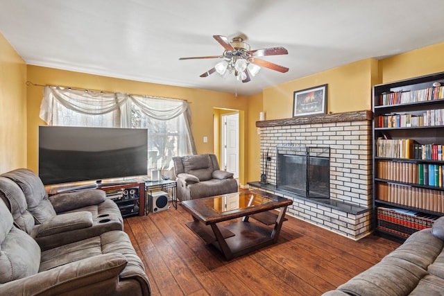 living area with a brick fireplace, ceiling fan, and wood finished floors