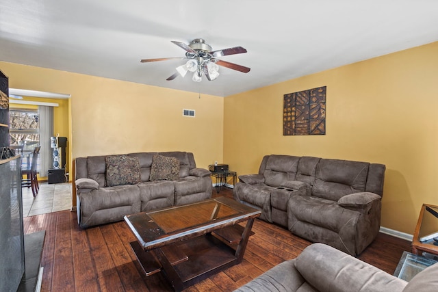 living area featuring dark wood-style flooring, visible vents, ceiling fan, and baseboards