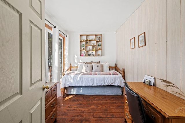 bedroom with dark wood-style flooring and wood walls