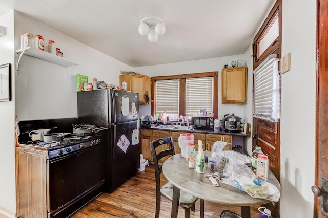 kitchen with dark countertops, black appliances, and wood finished floors