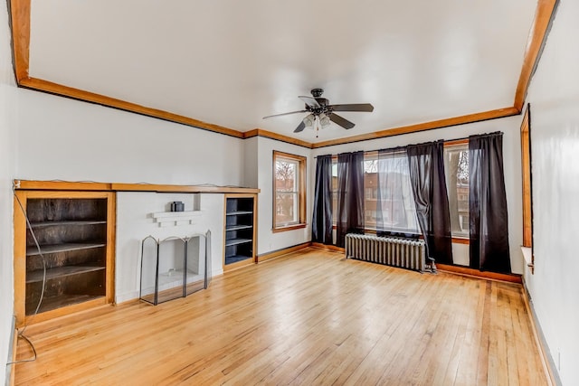 unfurnished living room featuring baseboards, radiator, ornamental molding, wood finished floors, and a brick fireplace