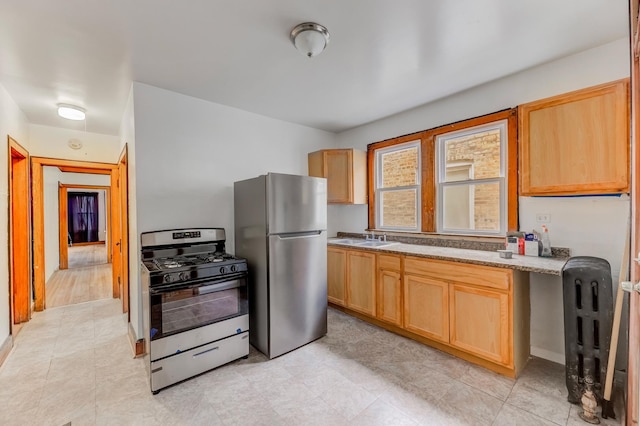 kitchen featuring stainless steel appliances, light brown cabinetry, and a sink