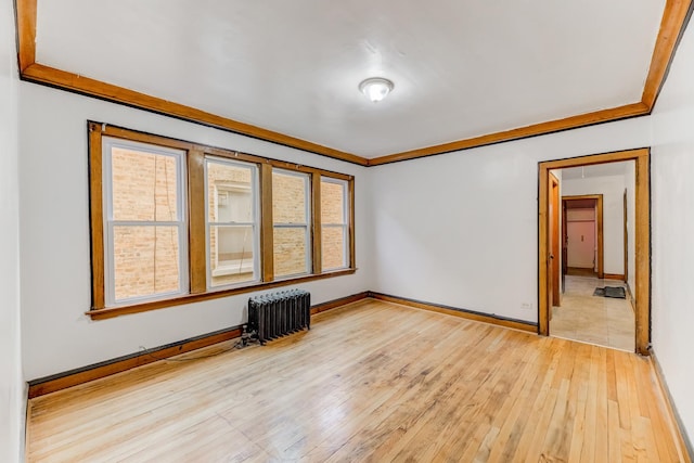 unfurnished room featuring baseboards, crown molding, radiator heating unit, and wood finished floors