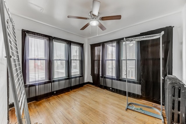 unfurnished room with a ceiling fan, radiator, and wood finished floors