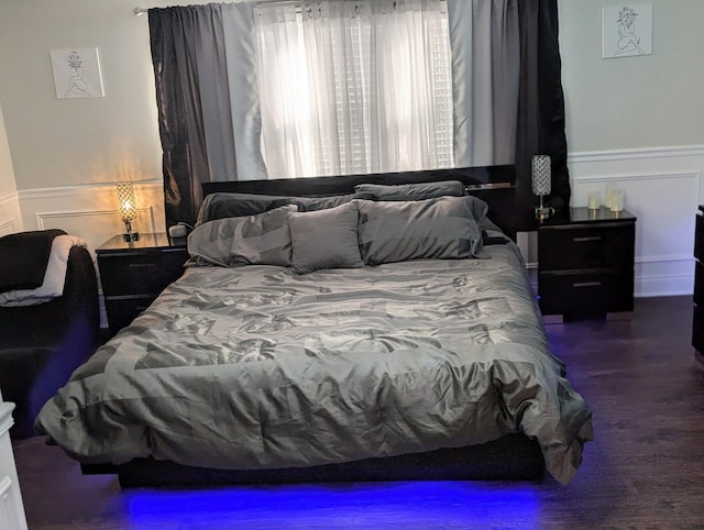 bedroom featuring dark wood finished floors and wainscoting