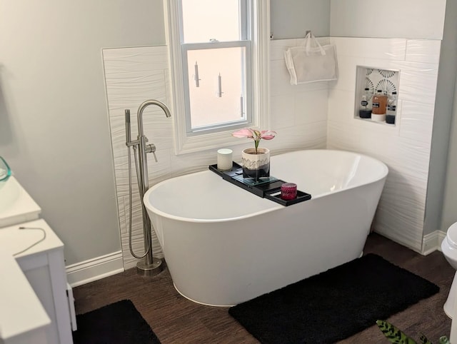 bathroom with a soaking tub, tile walls, toilet, and wood finished floors