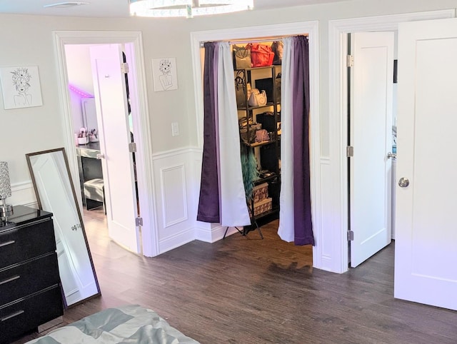 bedroom featuring dark wood-style floors, a closet, and a wainscoted wall