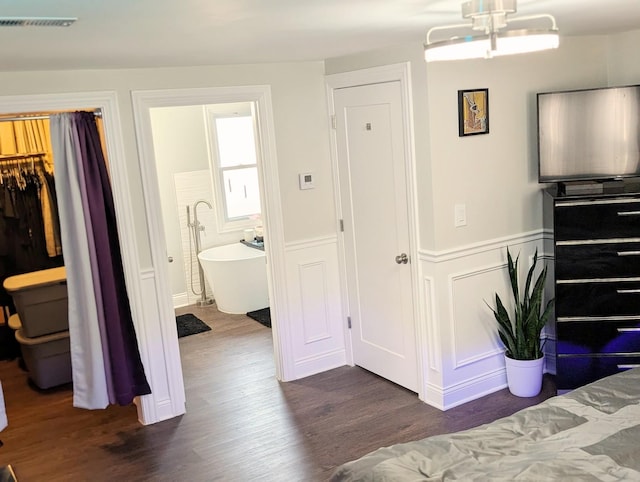 bedroom with dark wood-style flooring, wainscoting, a closet, and visible vents