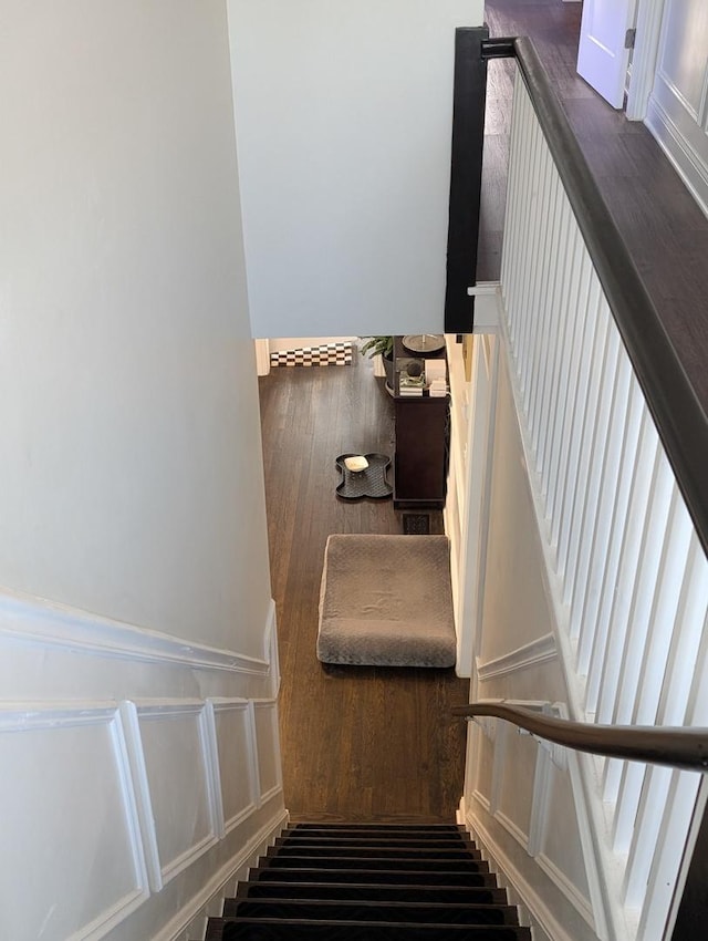 stairs featuring wainscoting and a decorative wall