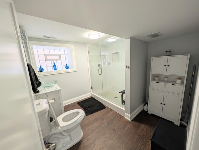 full bath featuring toilet, a stall shower, wood finished floors, and visible vents