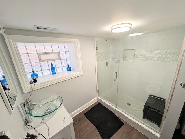 full bathroom with wood finished floors, vanity, baseboards, visible vents, and a shower stall