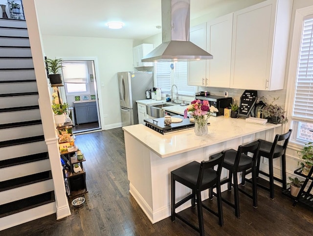 kitchen with white cabinets, island exhaust hood, and a kitchen bar