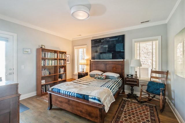 bedroom with baseboards, crown molding, visible vents, and wood finished floors