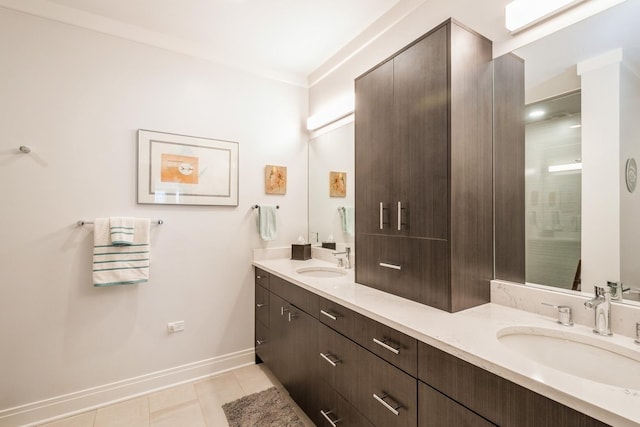 bathroom featuring tile patterned flooring, a sink, baseboards, and double vanity