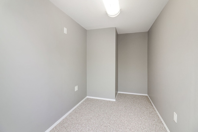 empty room featuring light carpet and baseboards