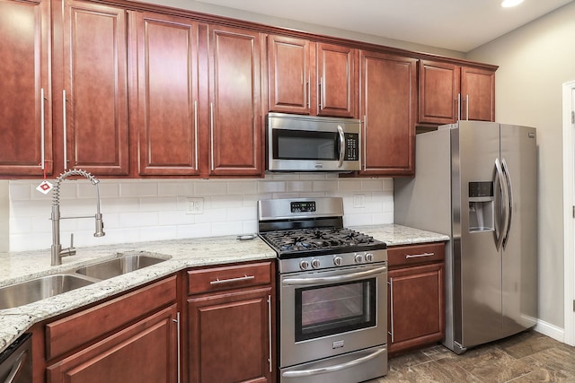 kitchen featuring stainless steel appliances, a sink, decorative backsplash, and light stone countertops