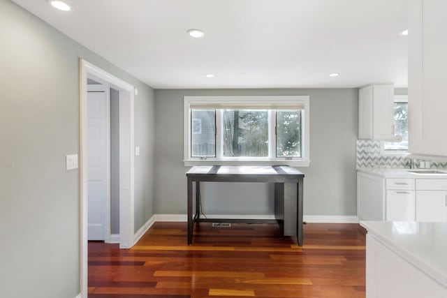 kitchen with dark wood-style floors, tasteful backsplash, light countertops, white cabinetry, and baseboards