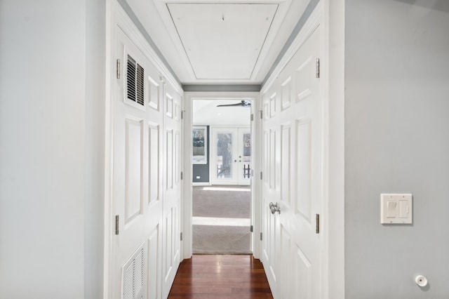 hall featuring dark wood-style floors, attic access, and visible vents