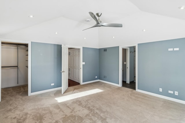 unfurnished bedroom featuring lofted ceiling, light colored carpet, visible vents, baseboards, and a spacious closet