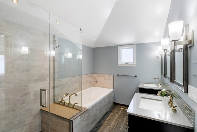 bathroom featuring lofted ceiling, a garden tub, a shower stall, and a sink