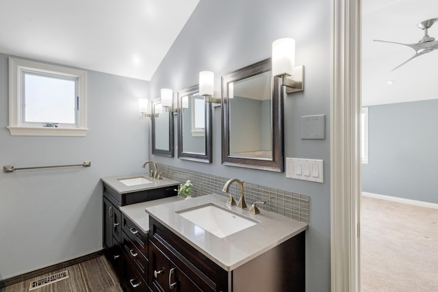 bathroom featuring lofted ceiling, a sink, visible vents, and decorative backsplash