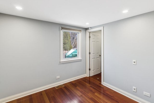 unfurnished room with dark wood-style floors, visible vents, baseboards, and recessed lighting