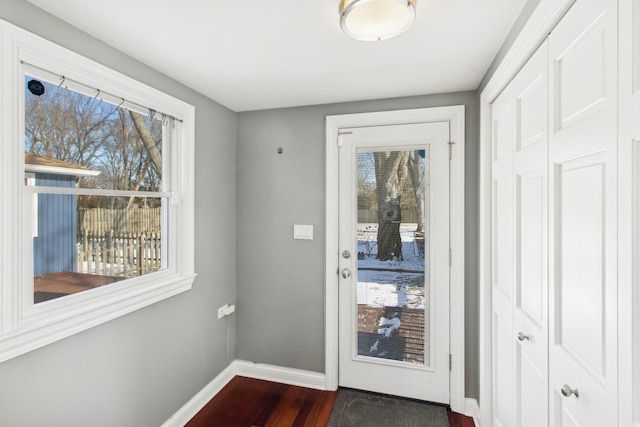 doorway with dark wood-style floors, plenty of natural light, and baseboards