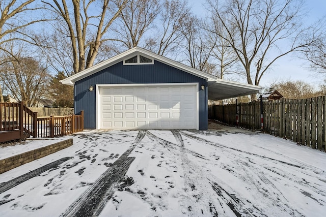 snow covered garage featuring a garage and fence