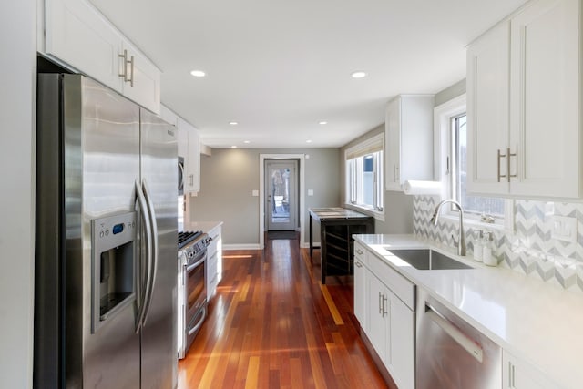 kitchen with white cabinets, decorative backsplash, appliances with stainless steel finishes, light countertops, and a sink