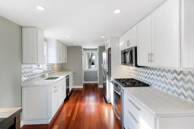 kitchen with a sink, stainless steel appliances, light countertops, and white cabinets