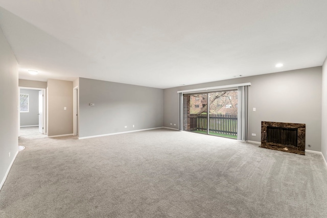 unfurnished living room featuring recessed lighting, light carpet, a fireplace, and baseboards