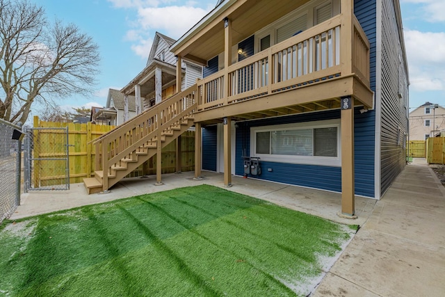 rear view of house with a yard, stairway, and fence