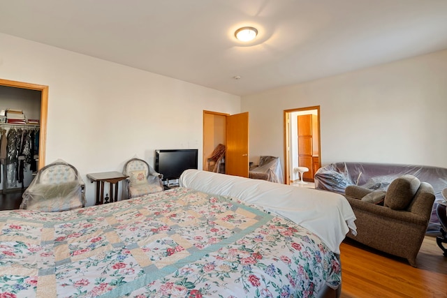 bedroom with a walk in closet, a closet, and wood finished floors