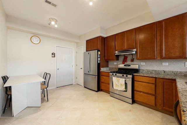 kitchen featuring stainless steel appliances, visible vents, backsplash, light stone countertops, and under cabinet range hood