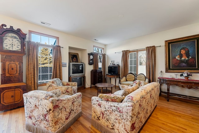 living area featuring light wood-type flooring, visible vents, and plenty of natural light