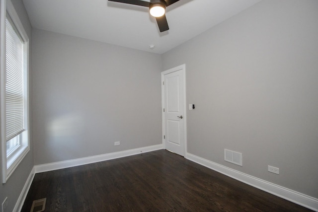 spare room with dark wood-style floors, baseboards, visible vents, and a ceiling fan