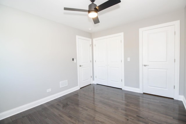 unfurnished bedroom featuring a ceiling fan, a closet, baseboards, and dark wood-type flooring